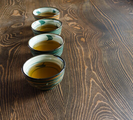 Four tea bowls are hardly behind each other. Fragrant herbal healing tea is poured into a mug. Background of wooden countertops, boards made of natural textured wood. Tea ceremony. Time to rest.