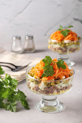 Salad with Korean carrots, meat and canned peas in transparent salad bowls a light gray background