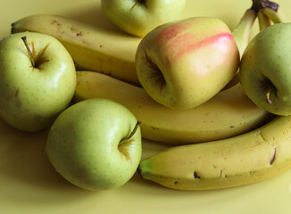 juicy apples and ripe bananas on a yellow background close up