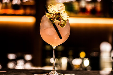 glass of a pink cocktail decorated with an orchid flower