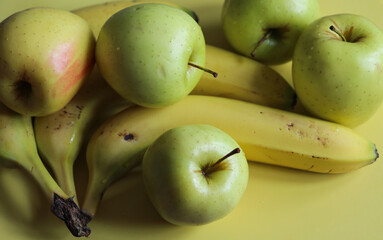 juicy apples and ripe bananas on a yellow background close up