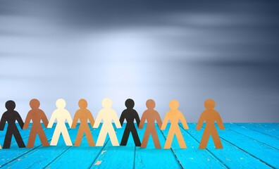 Row of paper people holding hands on table