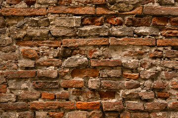 Ancient brick stone wall. Antique half-destroyed wall with brown handmade brickwork. Close up shot. Abstract texture or background.