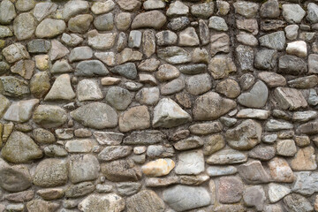 Part of the wall is made of natural stone of gray-brown color with cement mortar in the street. Background