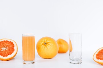 Glass with grapefruit juice and whole and sliced grapefruit on the background