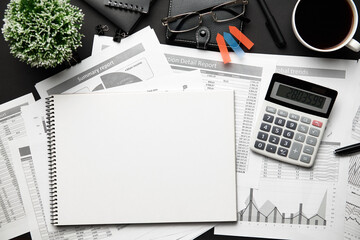 Top view of modern black office desk with notebook, pencil, financial reports and a lot of things. Flat lay table layout.