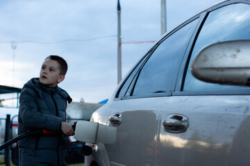 a boy refuels a car at a gas station. gas station. petrol