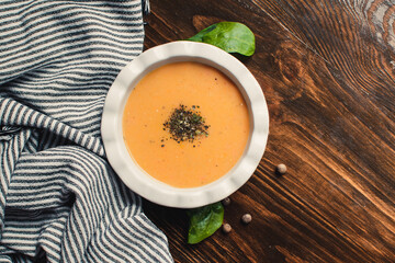 Pumpkin and carrot cream soup on the dark wooden table. Healthy food.