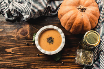 Pumpkin and carrot cream soup on the dark wooden table. Healthy food.