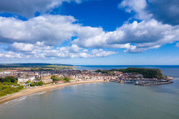 Obraz premium Aerial photo of the town centre of Scarborough in East Yorkshire in the UK showing the coastal beach and harbour with boats and the Scarborough Castle on a bright sunny summers day