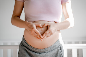 Pregnant woman folded her hands on a heart shaped belly, round belly, expecting a baby, love and care concept, health and beauty - obrazy, fototapety, plakaty