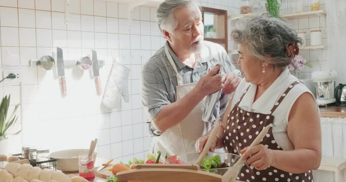 Couple senior Asian elder happy living making salad in home kitchen.