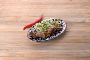 skewers of lamb with hot peppers on wooden background