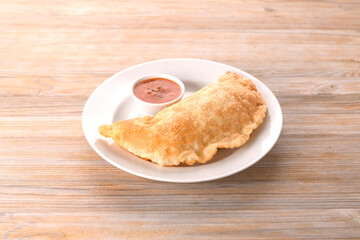 fried cheburek on a white plate with sauce