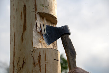 an axe in the hands of a carpenter cuts a log