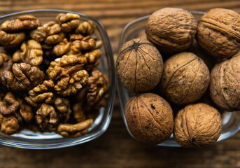 Whole and sheled walnut in a small plates on a vintage wooden table as a background. Walnuts is a healthy vegetarian protein nutritious food. Natural nuts snacks.