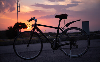 Fototapeta na wymiar Silhouette of a bicycle with clouds and sunset in the background