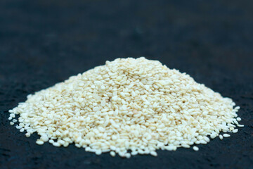 A handful of sesame seeds on a black background.
Close-up.