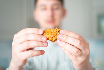 A hungry man looks at a chicken. Guy twists a fried chicken wing in his hands
