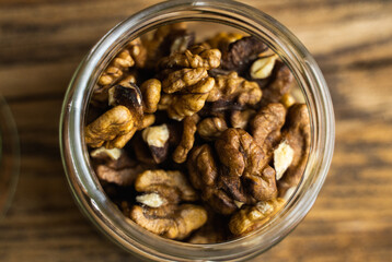 Walnut in a small jar on a vintage wooden table as a background with a copy space. Walnut is a healthy vegetarian protein nutritious food. Natural nuts snacks.