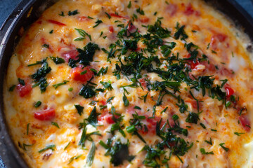 omelet with tomatoes and herbs in a pan, cooking, delicious nutritious breakfast