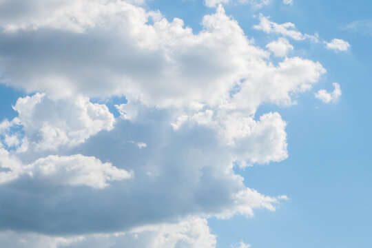 Several amorphous clouds merging into one against the background of a large clear blue sky