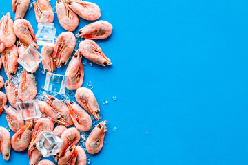 Shrimps - frozen, with ice, at shell - on blue backgroud frame copy space