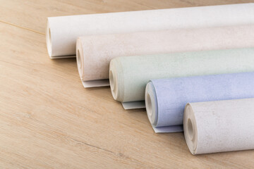 rolls of multi-colored paper wallpaper on a wooden table