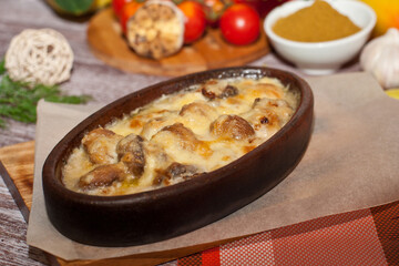 casserole with cheese and meat in a clay form on a wooden table