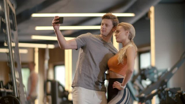 Smiling couple making selfie photo at gym. Fit man taking picture in sport club