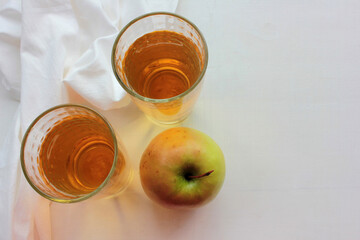Top view of apple juice in glasses and green apple on the white wooden table with copy space