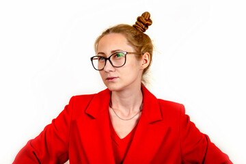 A beautiful young stylish girl is dressed in a red coat and glasses, her hair is on her head, and she looks away thoughtfully. The concept of students and youth. Isolated on a white background.