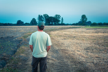 Male farmer looks at dry farmland