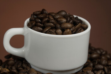 White mug with coffee grains sprinkled with coffee grains on a background