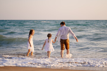 wet dad and daughters swimming in sea in clothes, playing and having fun.