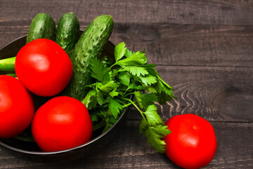 Seasonal vegetables on a plate. Tomatoes, cucumbers, chives, parsley.