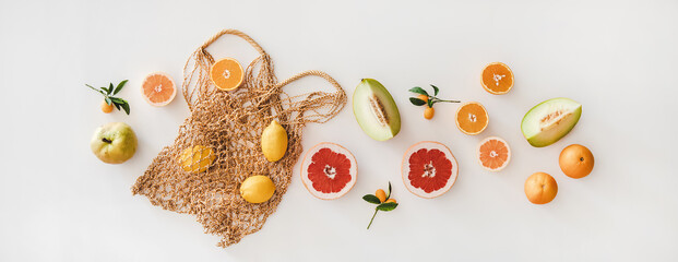 Summer mood layout. Flat-lay of summer natural net bag and various fresh fruits over white plain background, top view