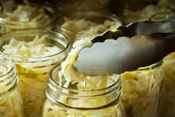Homemade Sauerkraut, a Fermented Food; Finished Product Being Put into Jars with Tongs