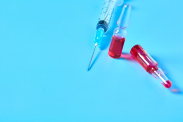 Disposable syringes and red vaccine on blue background. Healthcare and medical concept