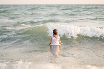 teenager girl in dress swims in sea with high waves. entertainment in vacation. 