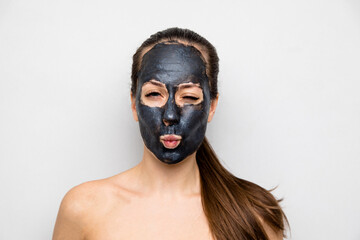 portrait of a beautiful young woman who does facial cosmetic procedures, skin with clay, advertising facial masks