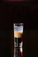 Cocktail B 52 close-up with different layers of liquid in a glass. Vertical photo, side view