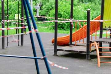 The play park of amusement and sports for young children is wrapped in red barrier tape. Outside. Prohibition of outdoor walks, prevention of the coronavirus influenza virus covid-19. selective focus