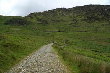 A figure in the far distance walking Watkins Path up to the peak of Mount Snowdon in Snowdonia National Park in North Wales, UK