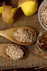 barley on wooden spoons, spices in glass jars next to dried mushrooms and raw potatoes