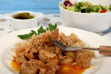A piece of meat on a fork and boiled barley on a white plateA piece of meat on a fork and millet on a white plate