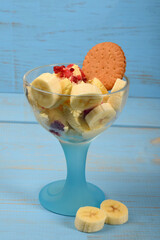 ice cream dessert with banana pieces and frozen raspberries and chocolate cake on a blue background
