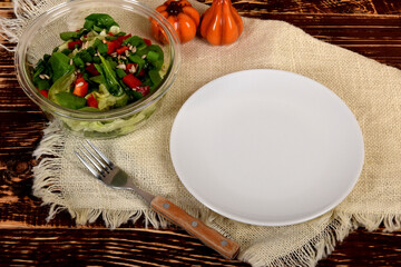 empty white plate next to the glass bowl with lettuce