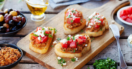 Bruschetta with olive tapenade and fresh tomatoes on cutting board. Wooden background. Close up.