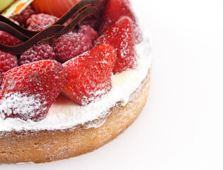 Close-up of fruit tart with strawberries, raspberries and chocolate decorations isolated on white background.